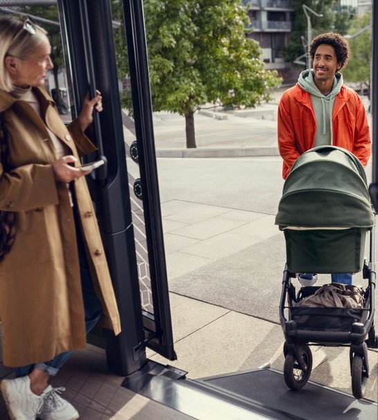 [Translate to Deutsch:] a man entering the mover with a buggie, a woman standing next to the door